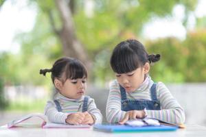 Two student little Asian girls reading the book on table photo