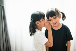 happy little Asian siblings sharing secrets photo