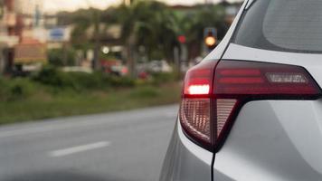 La parte trasera del coche enciende la señal de freno de luz. en carretera asphlt con ciudad al lado. foto