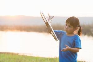 dreams of flight child playing with toy airplane against the sky at sunset photo