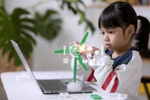 renewable energy, science, and technology concept - happy children with laptop computers, wind energy hologram,s and wind turbine models and icons. photo