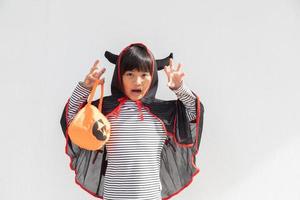 Funny halloween kid concept, little cute girl with costume halloween ghost scary he holding orange pumpkin ghost on hand, on white background photo