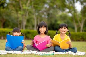 tres niños leyendo en el parque. foto