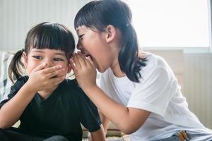 happy little Asian siblings sharing secrets photo