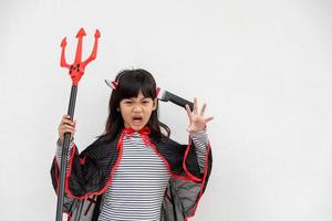 niña asiática disfrazada de demonio con tridente negro y rojo, feliz concepto de halloween foto