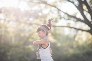 niña feliz corriendo en el parque en verano en la naturaleza. llamarada cálida de la luz del sol. el pequeño asiático corre en un parque. deportes al aire libre y fitness, ejercicio y aprendizaje de competencias para el desarrollo de los niños. foto