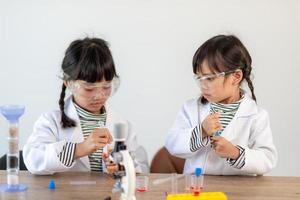 education, science, chemistry and children concept - kids or students with test tube making experiment at school laboratory photo