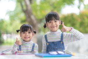 Two student little Asian girls reading the book on table photo