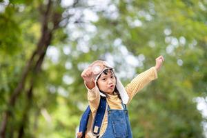 A cute little girl dressed in a cap and glasses of a pilot. The child dreams of becoming a pilot. photo