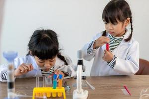 education, science, chemistry and children concept - kids or students with test tube making experiment at school laboratory photo