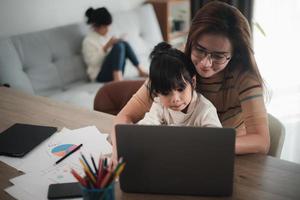 madre trabajando en la oficina en casa con su hija en su regazo foto