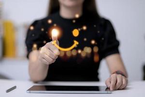 el consumidor respondió la encuesta de forma conceptual. el cliente crea un símbolo sonriente de cara feliz con un bolígrafo digital. la noción de felicidad del cliente y experiencia de servicio. foto