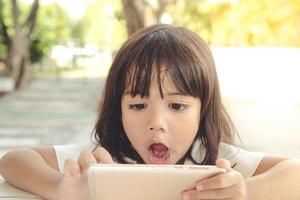 Shocked and surprised little girl on the internet with digital tablet computer concept for amazement, astonishment, making a mistake, stunned and speechless or seeing something he should not see photo