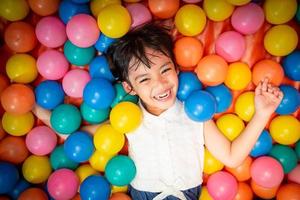 Happy asian girl playing in colorful balls pool photo