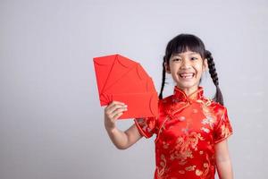 Happy Little Asian girl in Chinese traditional dress smiling and holding a red envelope. Happy Chinese new year concept. photo