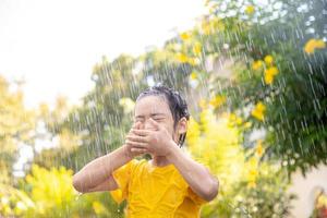 Happy Asian little child girl having fun to play with the rain in the sunlight photo