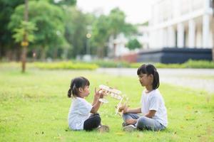 dos niños pequeños jugando con un avión de juguete de cartón en el parque durante el día. concepto de juego feliz. niño divirtiéndose al aire libre. foto