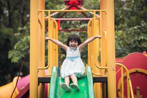 Happy girl on slide playground area photo