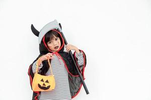 Children girl wearing mysterious Halloween dress holding a scary pumpkin and sickle. photo