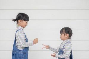 dos niños jugando en un juego de piedra, papel o tijera sobre fondo blanco foto