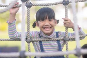 Cute children. Asian girl climbing in a rope playground structure at the adventure park photo