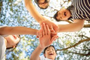 concepto de unidad. vista inferior de niños pequeños poniendo sus manos juntas foto