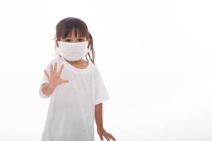 Coronavirus Covid-19.Stay at home Stay safe concept.Little girl wearing mask for protect.show stop hands gesture for stop corona virus outbreak.Coronavirus pandemic virus symptoms.Home school photo