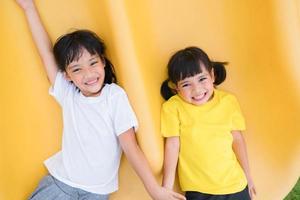 Child playing on outdoor playground. Kids play on school or kindergarten yard. Active kid on colorful slide and swing. Healthy summer activity for children. photo