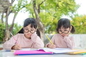 Two Asian Children Doing Homework Together at home photo