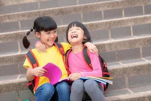 Two Little Girl reading a book together. Adorable Asian kids enjoying studying outdoors togther. Education, intelligence concept photo