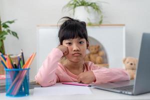 Unhappy little Caucasian girl child sit at table at home feel lazy unmotivated doing homework assignment. Upset distressed small 7s kid prepare school task, learn study with books. Education concept. photo