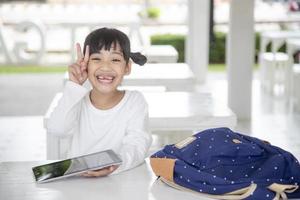 happy little girl using a tablet at home, smiling cute preschool child kid looking at modern device screen, having fun with the gadget, watching cartoons, playing game photo