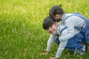 Asian Little girl with elder sister at a park riding on her back photo