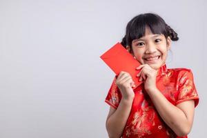 Happy Little Asian girl in Chinese traditional dress smiling and holding a red envelope. Happy Chinese new year concept. photo