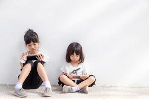 Concept kids and gadgets. Two little girls siblings sisters look at the phone. They hold a smartphone watch videos, learn, play games, speak online. Internet for children. photo