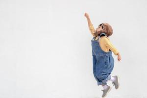 dreams of flight little child girl playing with a pilot hat on white background photo