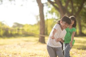 Children playing tug of war at the park on sunsut photo