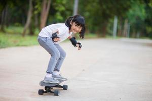 Cute little girl playing skateboard or surf skate in the skate park photo