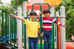 Cute little girls siblings having fun on playground outdoors on sunny summer day photo