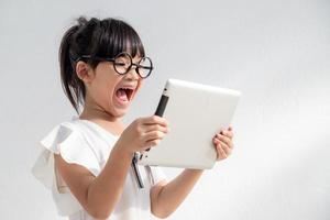 Shocked and surprised little girl on the internet with digital tablet computer concept for amazement, astonishment, making a mistake, stunned and speechless or seeing something he should not see photo