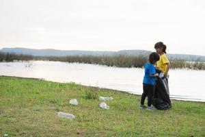 Cute girl while helping sibling to clean up garbage photo