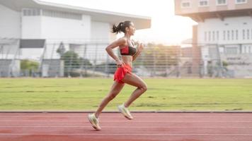 woman running during sunny morning on stadium track photo