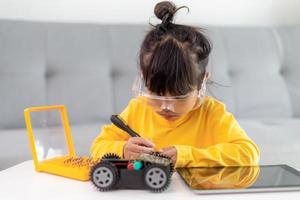 Little girls having fun in a workshop coding robot car photo