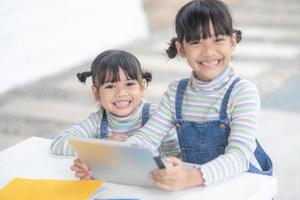 Two Asian little sisters playing with a digital tablet at home photo