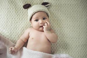 niña recién nacida posada en un recipiente sobre su espalda, sobre una manta de piel foto