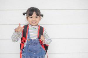 Portrait of little cute Asian girl with her thump up, advertisement concept, little Asian teenage thumps up with the white background and space photo