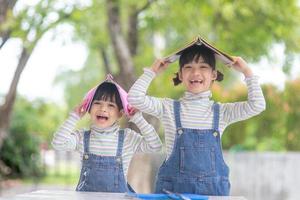 lindos niños asiáticos leyendo un libro sobre la mesa foto