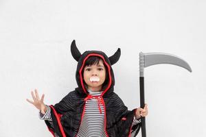 niña con un misterioso vestido de halloween sosteniendo una hoz sobre fondo blanco foto