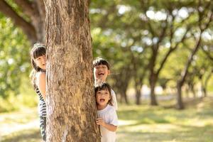 little girl is playing hide-and-seek hiding face in the park photo