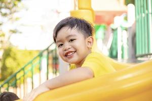 Child playing on the outdoor playground. Kids play in school or kindergarten yard. Active kid on colorful slide and swing. Healthy summer activity for children. photo